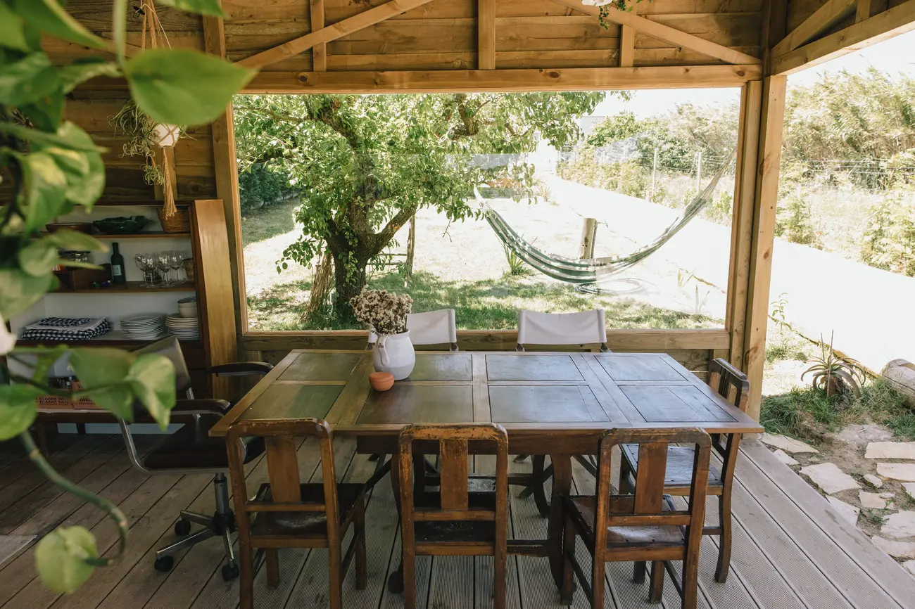Mesa de refeições exterior da Barraca, com rede ao fundo