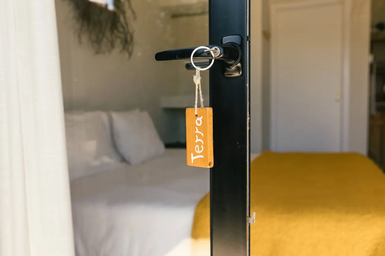 Chave da Terra pendurada na porta, cama mostarda ao fundo