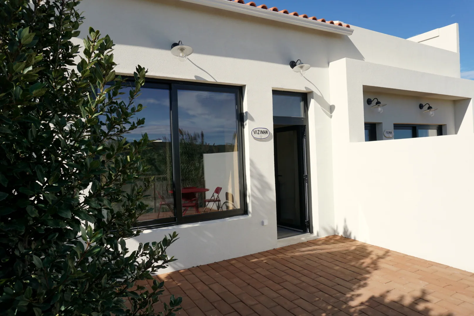 Eingang der Vizinha, mit Glastür und gefliestem Patio