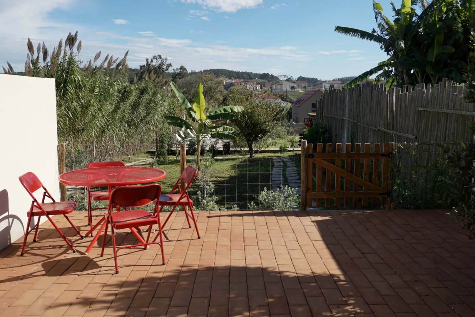 Eigener Patio der Vizinha, mit rotem Tisch und Stühlen und Blick auf den Garten